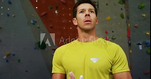 Man dusting his hand with chalk powder before climbing the artificial wall 4k