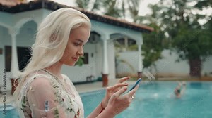 Portrait of a girl using the voice recognition of the phone and looking at cell phone near swimming pool in hotel on vacation tourist speech personal assistant natural language user interface