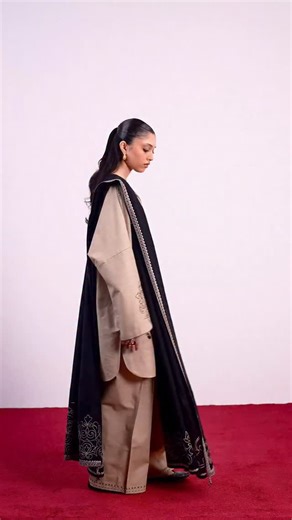 Zaha on Instagram: "FÉRA — defined by quiet drama, this ensemble unfolds in soft beige, anchored by striking black embroidery tracing the neckline and sleeves with artisanal precision. The relaxed kurta silhouette flows with ease, layered for winter warmth without losing its structured grace. A deep black woolen shawl and matching wide khaddar trousers complete the look, draping with fluid sophistication and offering cozy, season-ready layering. Minimal yet commanding, FÉRA balances heritage cra