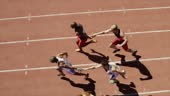 High angle view of male relay runners passing batons on track. They...