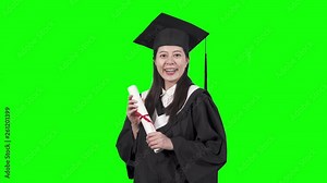 education graduation people concept. happy international korean student in mortar board and bachelor gown with diploma scroll. young asian college girl showing certificate of degree on green screen