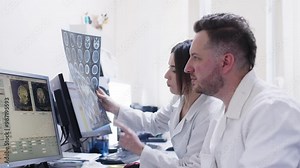 In the control room, doctors review scan results while a patient undergoes an MRI under the supervision of radiologists. These discussions are crucial for accurate diagnostics.