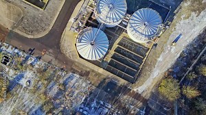 Aerial footage fo a large industrial chemical plant, showing pipelines, metal structures, cooling towers and chemical storage tanks.