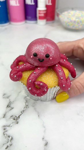 The octopus emoji 🐙🧁 but as a cupcake I used @colourmill raspberry chocolate drip to fill my silicone cake pop mold. When set I brushed it with pink lustre dust. I coloured my buttercream with colour mill raspberry oil blend. I used piping tip 12 for the arms and sprinkles for the eyes and smile. 🐙✨ #cupcake #cupcakedesign #cakedbyrach #octopus #cakedesign #cutebaking | Caked By Rach