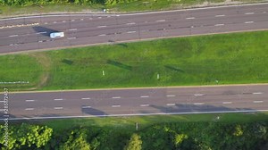 pan right over Bay Parkway at Jones Beach as the cars go about their way 2x speed on a sunny evening with new road pavement and green grass landscaping along the road