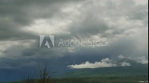 Stormy blue clouds are quickly approaching in the mountains, foreshadowing a strong thunderstorm and rain. Time lapse of accelerated movement of storm black clouds. Cyclone movement