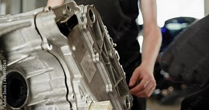 Mechanics Working on Electric Car Engine for Maintenance. Close-up of mechanics performing maintenance on an electric car engine. Working on disassembled motor. EV repair and service concept.