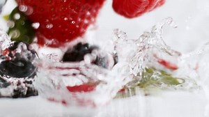A medley of berries splash into water.