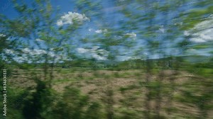 Scenic Tuscany landscape from a moving vehicle, blue skies above.