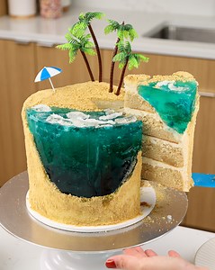 This beach-inspired cake is decorated with graham cracker crumbs and a gelatin ocean!! It's the ultimate summer cake! Get the recipe here: https://chelsweets.com/beach-cake/ | Chelsweets