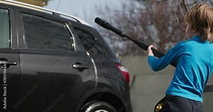Kid Uses Pressure Car Washer to Clean Auto in Backyard. Child Helps Washing Vehicle. 4K Slow motion 60 fps 10-bit