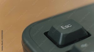 Human finger repeatedly pressing the escape key on a black keyboard.