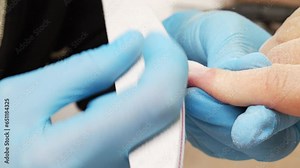 Nail file processing. Manicurist files the shape of the nails with a special nail file, close up view. The manicurist shapes the nails with a nail file. Process of nail care in a beauty salon. Closeup
