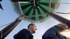 Adventure love couple on hot air balloon watermelon. Man and woman kiss hug love each other. Burner directing flame into envelope. Fly in morning blue sky. Happy people take selfie in hot air ballon.