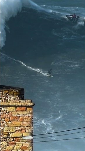 Surfer rides massive wave as spectators watch in Nazaré, Portugal