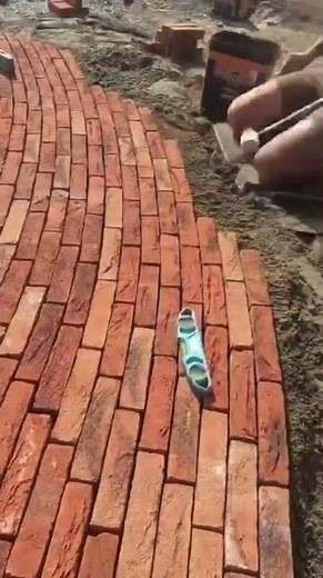 Shaping a smooth brick walkway as each precise tap sets the path in place