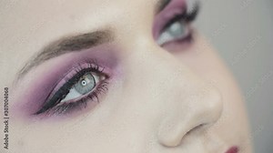 Smoky eyes. Pink make up. Close-up of beautiful eyes of a girl with pink shades. The girl opens her eyes. Looks at up. Clear skin.