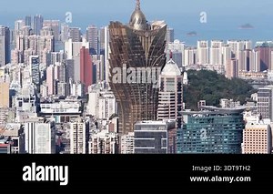 Macau, Special administrative region of China, China, February 16, 2026: Aerial view of the iconic grand lisboa hotel, a golden lotus shaped skyscraper, dominating the densely populated urban landscape of the macau peninsula against the backdrop of Stock Video Footage - Alamy
