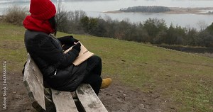 Travel woman with red hat in black jacket write on notebook, make notes, drawing some sketche against the river view, local travel, mental health. Stock Video