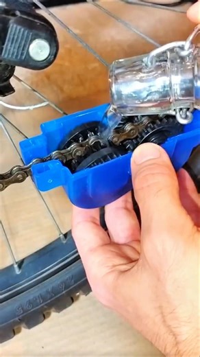Worker cleans bicycle chain using specialized cleaning tool