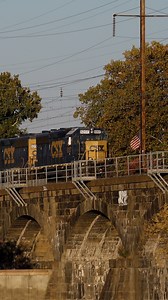 A pair of CSX engines, operating as Conrail Shared Assets Operations train YPMO-33, cross the grand stone-arch bridge across the Delaware River from Trenton, New Jersey into Morrisville, Pennsylvania on October 21, 2024. | Trainiac Productions