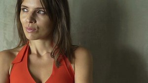 Sad, pensive woman standing by the wall