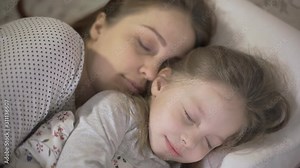 mother and young daughter sleeping in bed and hugging each other ,the relationship between parents and children