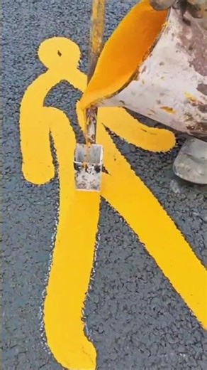 Manually painting the pedestrian crossing marks on the road surface using bright and clear colors.