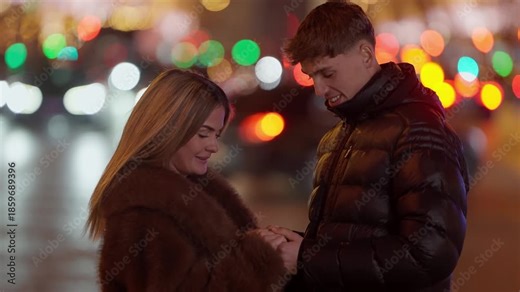 A young couple embraces on a city street in Paris at night Bokeh lights create a romantic atmosphere The scene captures a moment of love and connection between the two lovers in France.