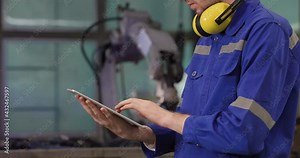 Professional industrial engineer caucasian man using digital tablet for programming control automation robot arms machine for composites material in manufacturing industry. Technology or innovation.