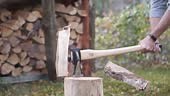Wood is split with a sharp axe on a stump, filmed in slow motion....