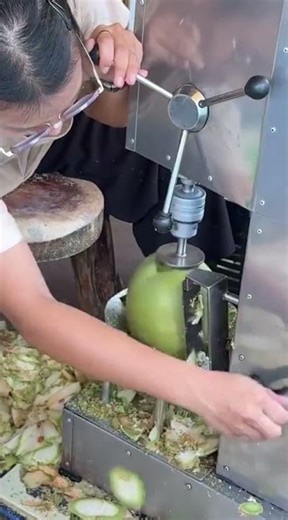 the process of peeling a coconut using a special tool to make it easier for someone to open it