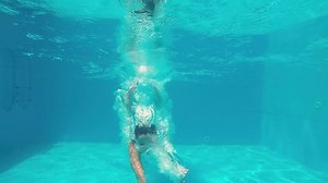 clip-1015804810-young-girl-white-bikini-swims-under-water