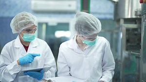 women factory workers check machine systems at the industrial factory. Women working in clean rooms for beverage and food production. Female worker recording data at the control panel.