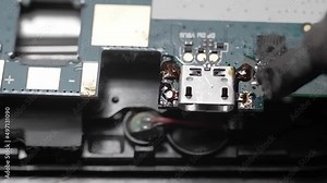 Repair of the printed circuit board by soldering close-up. Soldering the motherboard of a tablet PC with a soldering iron in the workshop. Repair of the power connector Stock Video