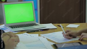 Wood Desk and thin laptop with Screen For Mock Up, with space for text, working men and women with financial timetable entries and making a mark