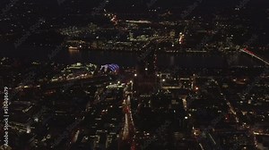 Forwards fly above city at night. City lights showing streets and bridge over Rhine river. Cologne, Germany