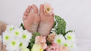 women's feet in fresh flowers. Summer lifestyle portrait of the legs of an attractive girl with wild flower buds between her fingers. I enjoy life, nature. The legs are in focus, the flowers are blur