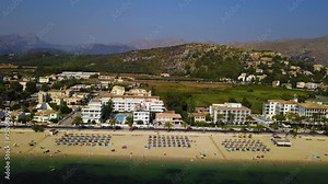 Playa del port de pollenca with sunbathers and parasols, mallorca, spain, on a sunny day, aerial view