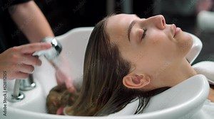 Hairdresser Washing Woman's Hair In Salon