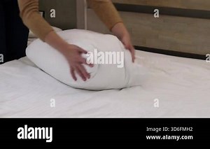 Fluffing a pillow, close-up. Female hands fluffing a pillow. Apartment or hotel cleaning concept. Morning routine. Close-up of female hands fluffing a large pillow for a comfortable sleep