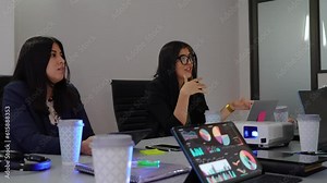 businesswomen conducting a business meeting in an office, woman CEO leader speaking with work team analyzing graphics on a tablet and using a projector on the table
