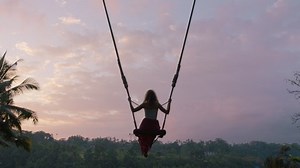 clip-1047372838-tourist-woman-swinging-over-tropical-jungle-sunrise
