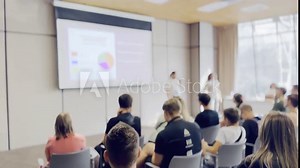 Attendees focus on a presentation with a slide show in a contemporary conference room. The scene captures a professional and educational atmosphere.