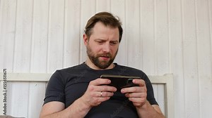 Man using his cellphone. Handsome guy use mobile phone at home. Male browses social networks, gaming, does shopping online, chats with friends, writes or reads messages. Close up. 4k video footage