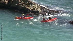 Yellow canoe paddling in the sea through a gap in some rocks. Stock Video