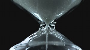 Glass hourglass close up on a black background - Free Stock Video