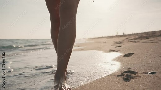 Video of closeup of young woman in bikini walking on the sand of the beach