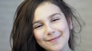 Portrait of happy adorable smiling child girl on light background. Natural Joy emotion. Happy face.