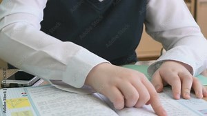 The pupil sitting at the school desk flips the pages of tutorial during the lesson